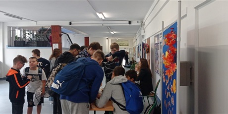 Powiększ grafikę: Grupa uczniów bierze udział w głosowaniu na korytarzu szkolnym.