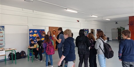 Powiększ grafikę: Grupa osób ustawiona jest w kolejce do głosowania na korytarzu szkolny.